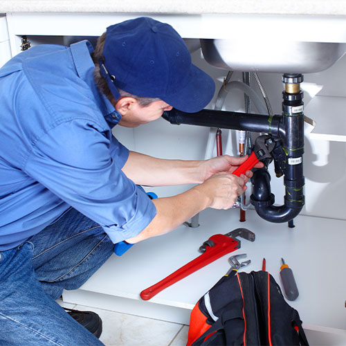 Plumbing service and repair specialist working on piping
